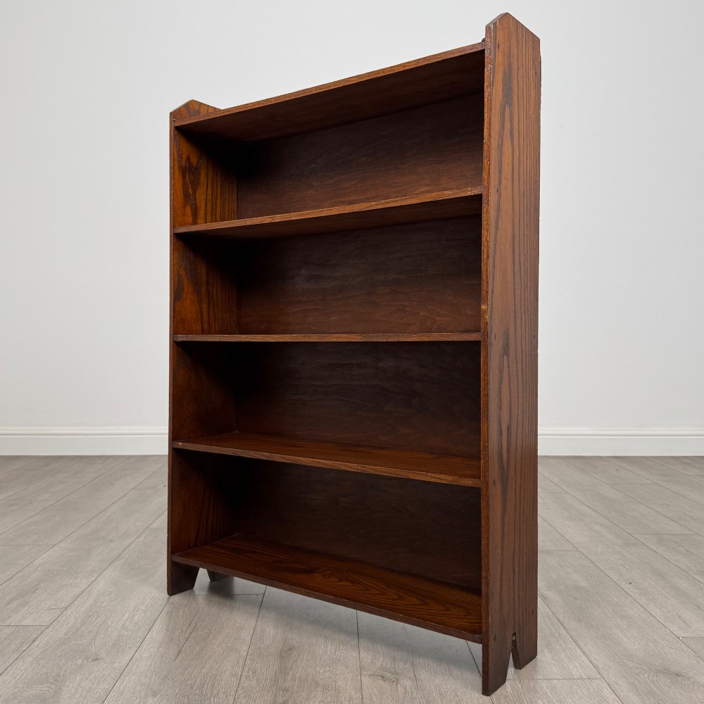 An Edwardian dark oak open bookcase featuring four fixed shelves and shaped side panels. View III