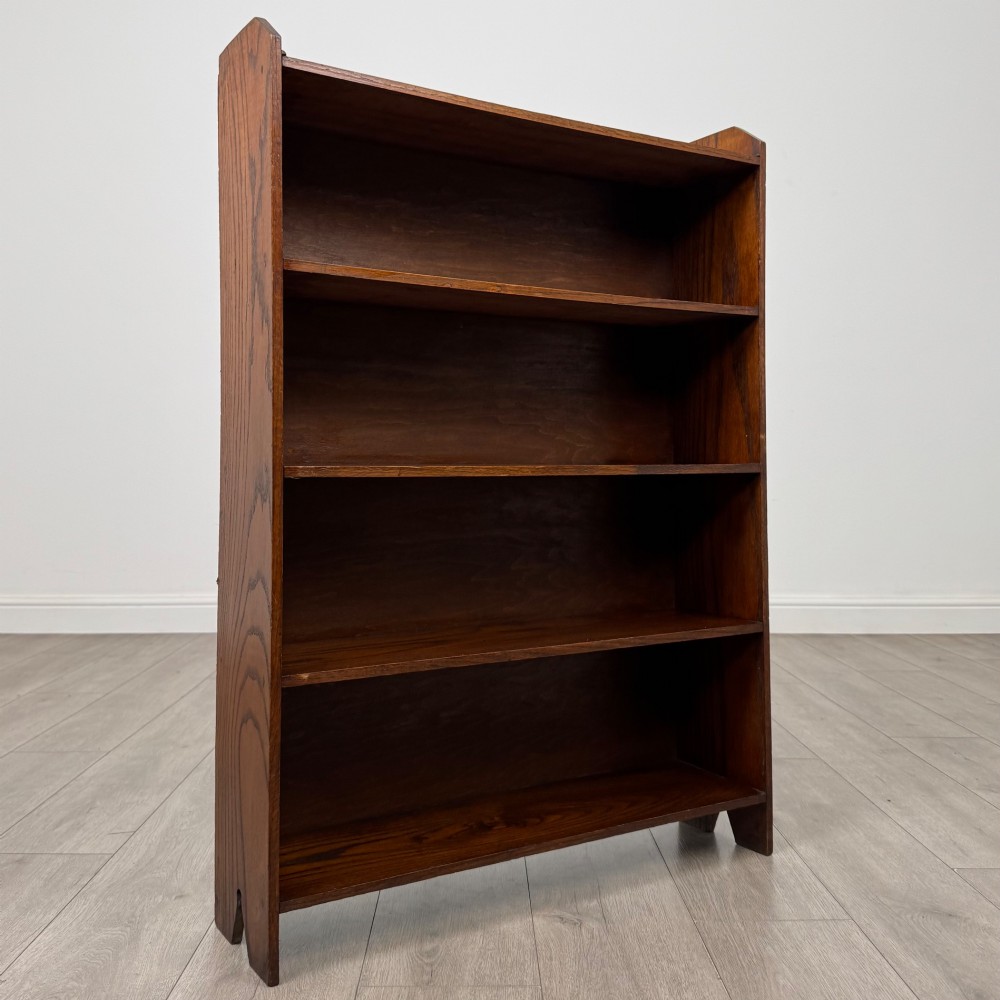 An Edwardian dark oak open bookcase featuring four fixed shelves and shaped side panels. View IX