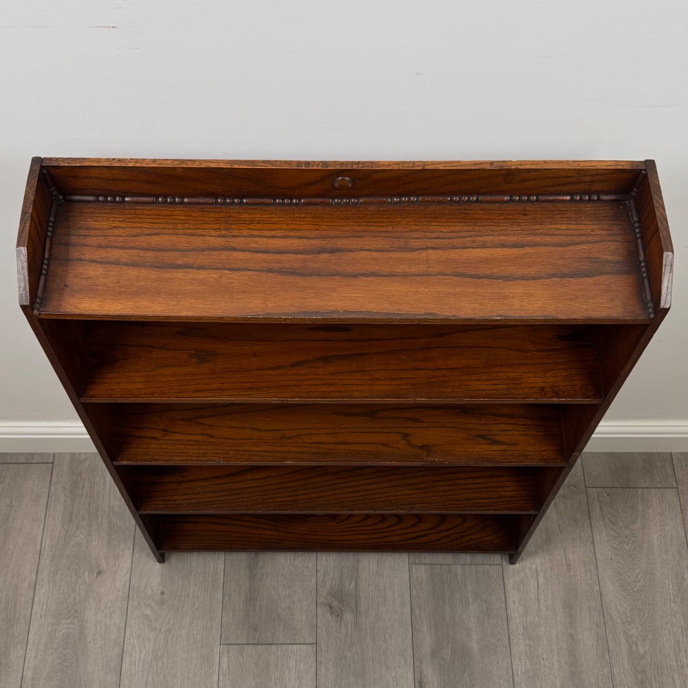 An Edwardian dark oak open bookcase featuring four fixed shelves and shaped side panels. View X