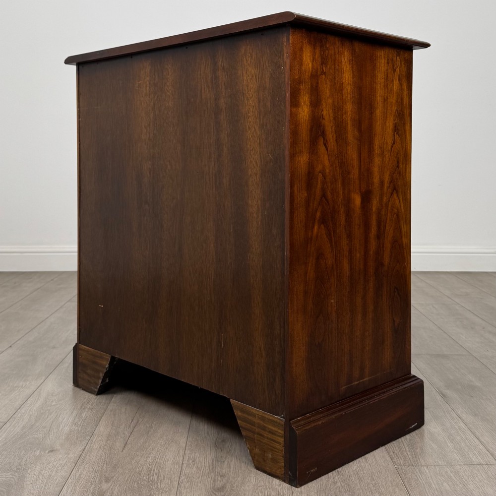 A 20th-century serpentine-front hardwood chest featuring four stacked drawers with brass drop ring handles and central brass escutcheons. View VI