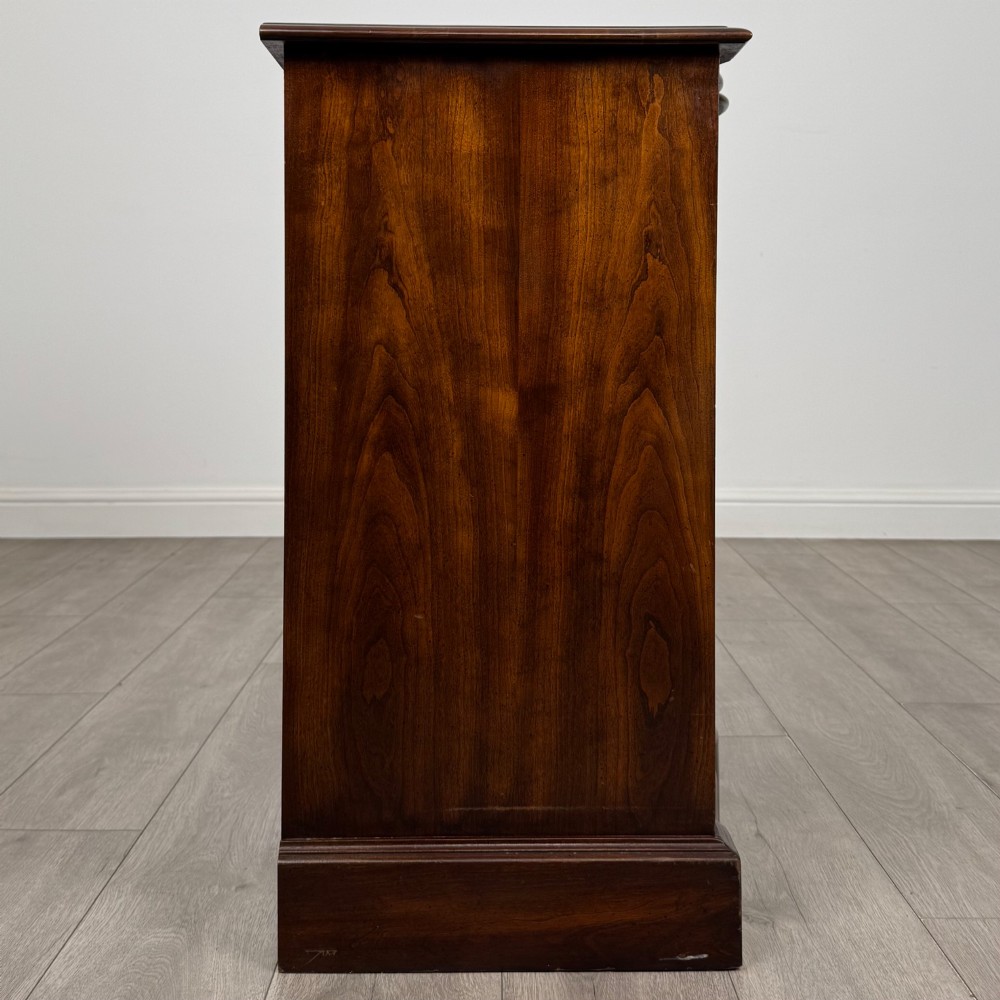 A 20th-century serpentine-front hardwood chest featuring four stacked drawers with brass drop ring handles and central brass escutcheons. View VII