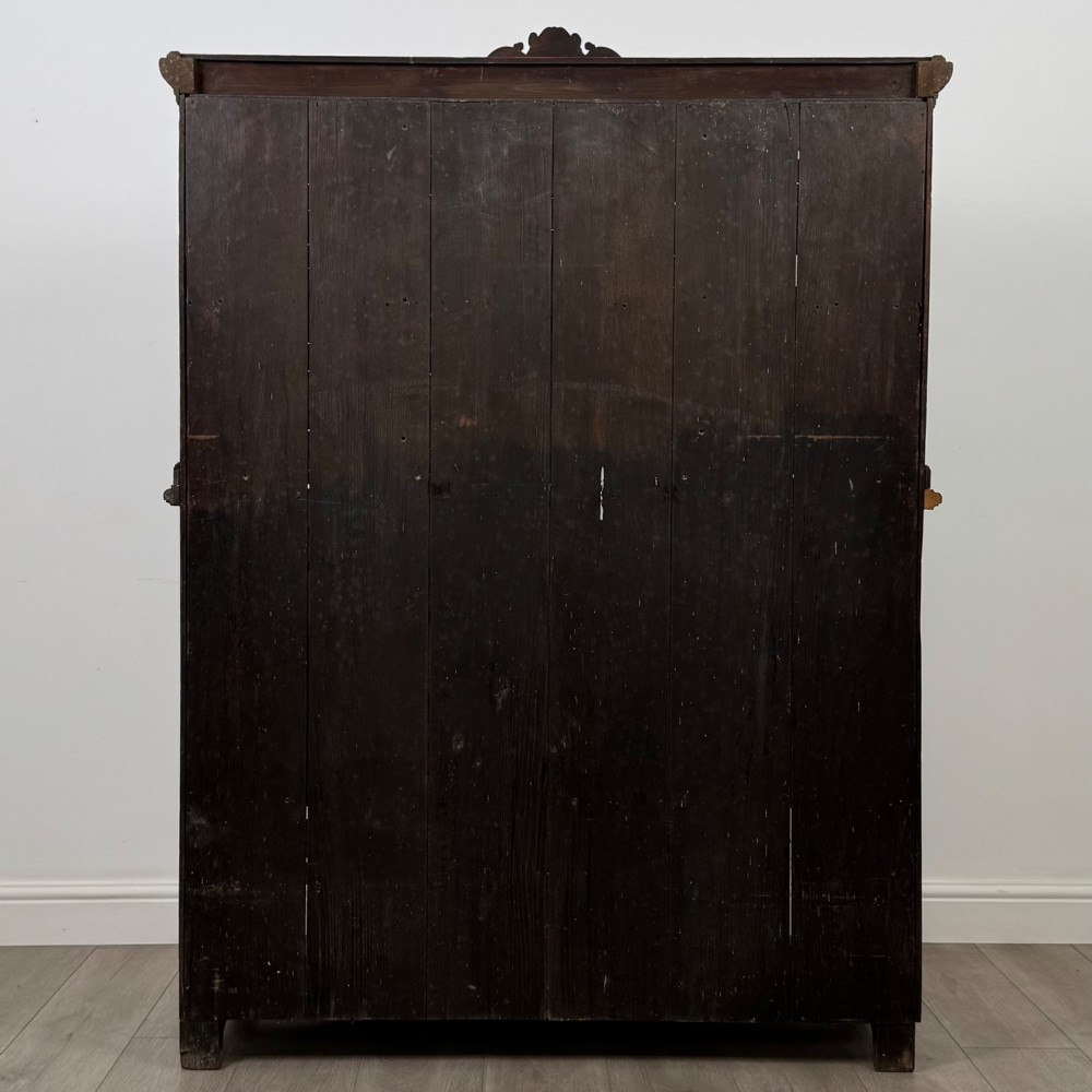 A 19th-century dark oak carved cupboard featuring an open top shelf, carved lion cresting, relief-carved panel doors with figures, and an open lower base. View VI