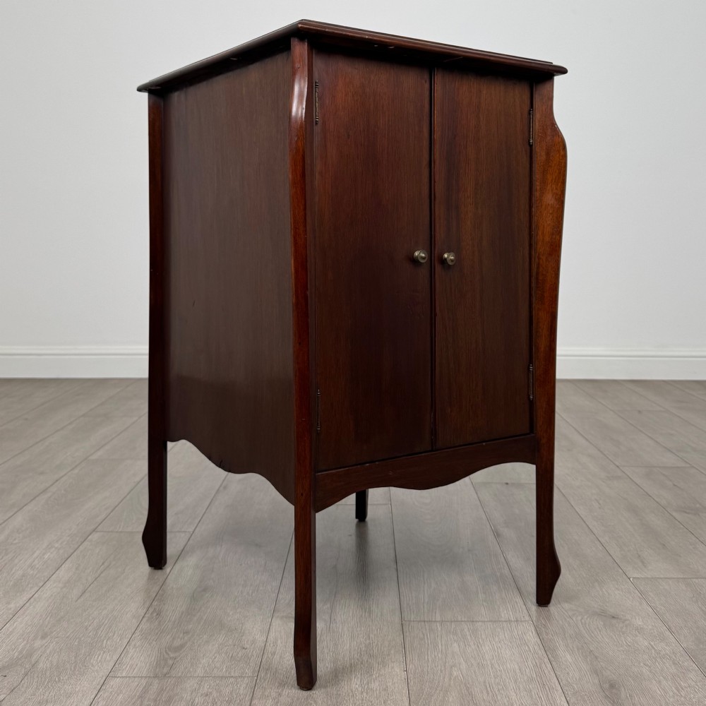 An antique Edwardian mahogany cabinet with double panelled doors, brass knobs, and elevated curved legs. View IX