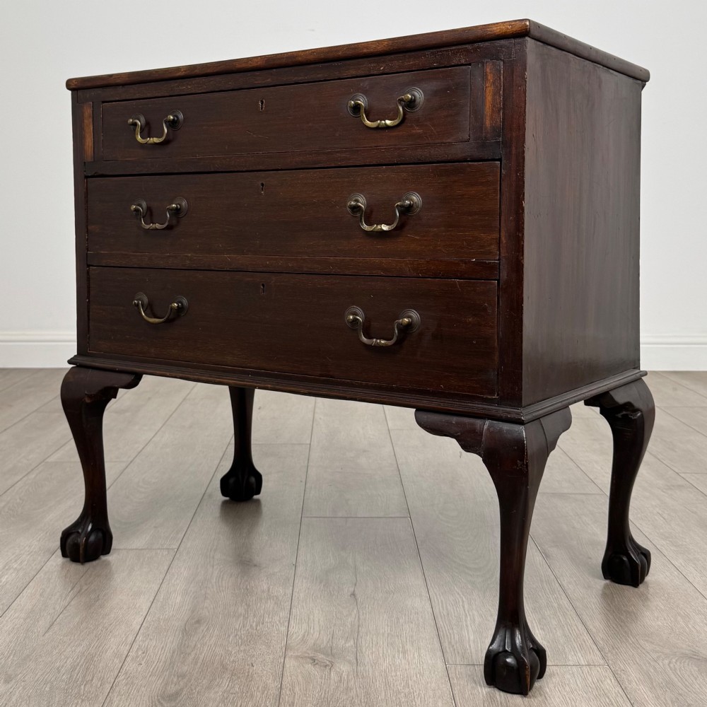 A dark mahogany chest of drawers featuring three long drawers with brass handles, raised on carved cabriole legs ending in ball and claw feet. View II