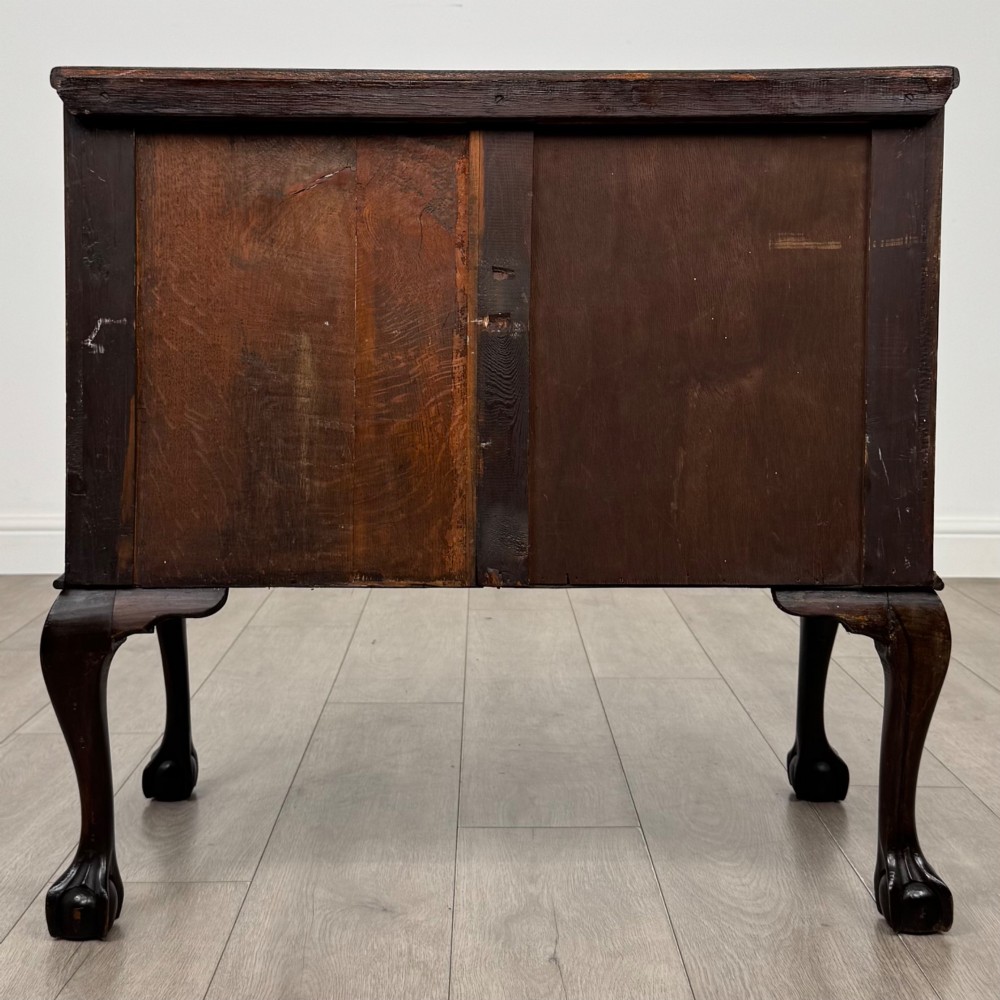 A dark mahogany chest of drawers featuring three long drawers with brass handles, raised on carved cabriole legs ending in ball and claw feet. View V
