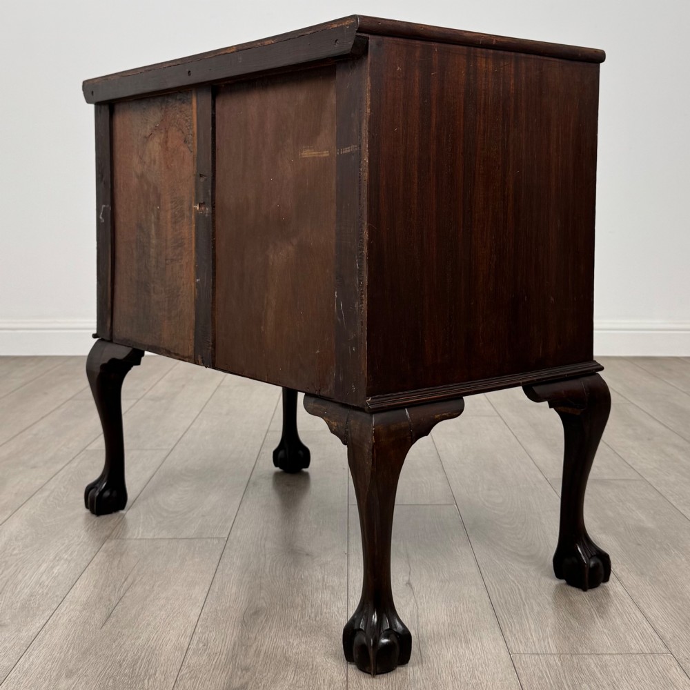 A dark mahogany chest of drawers featuring three long drawers with brass handles, raised on carved cabriole legs ending in ball and claw feet. View VI