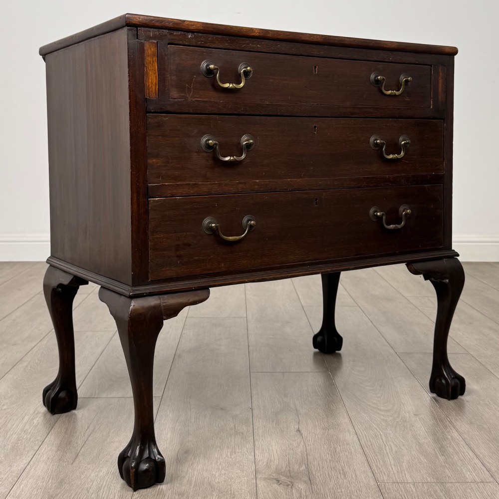 A dark mahogany chest of drawers featuring three long drawers with brass handles, raised on carved cabriole legs ending in ball and claw feet. View VIII