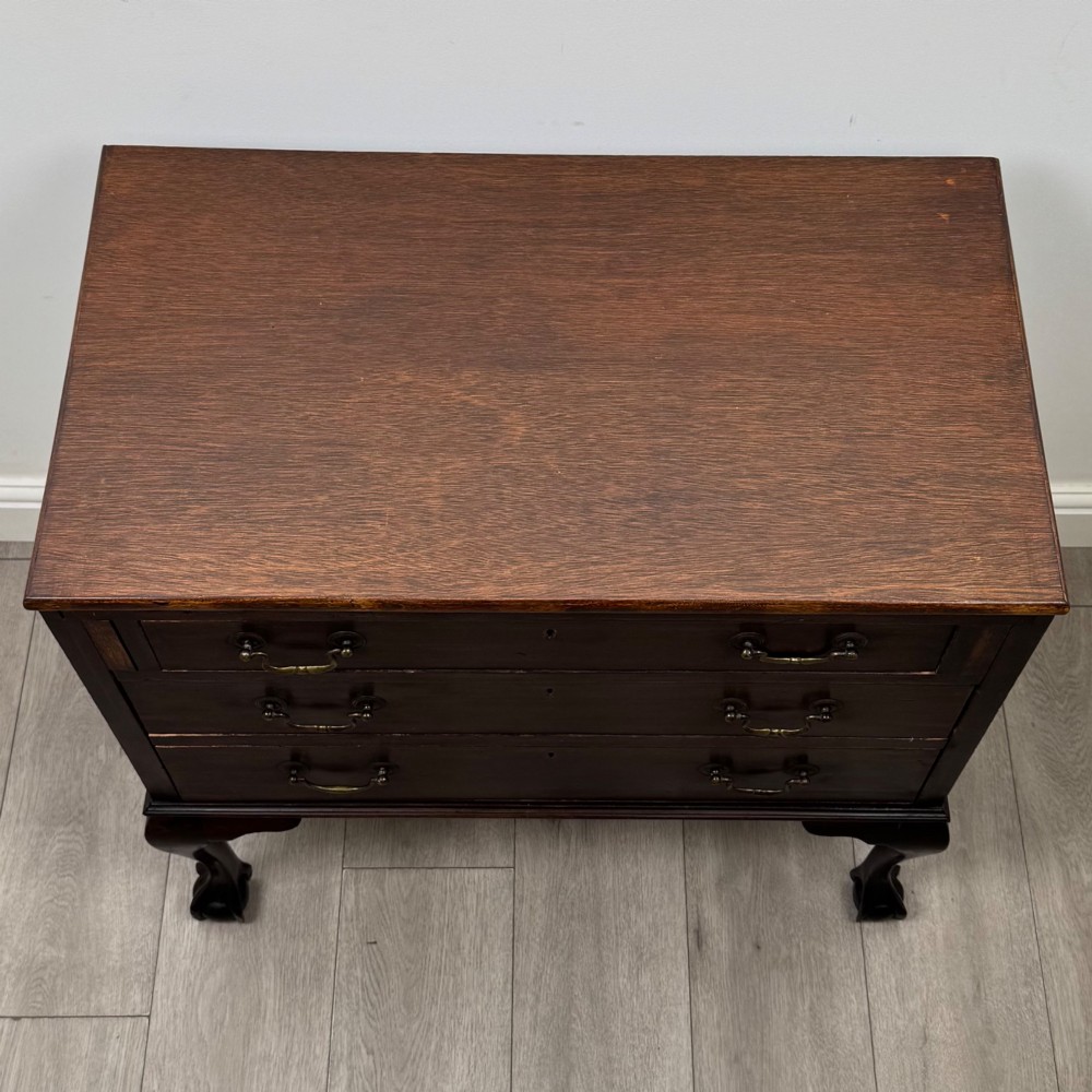 A dark mahogany chest of drawers featuring three long drawers with brass handles, raised on carved cabriole legs ending in ball and claw feet. View IX