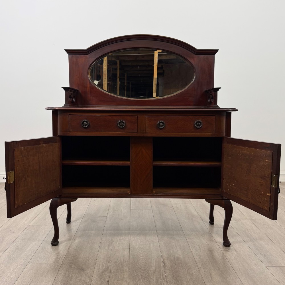 An antique Edwardian mahogany sideboard featuring a top section with a central oval mirror, two drawers, and a two-door cabinet below raised on cabriole legs. View II
