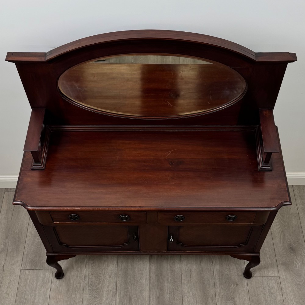 An antique Edwardian mahogany sideboard featuring a top section with a central oval mirror, two drawers, and a two-door cabinet below raised on cabriole legs. View X