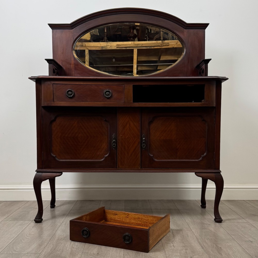 An antique Edwardian mahogany sideboard featuring a top section with a central oval mirror, two drawers, and a two-door cabinet below raised on cabriole legs. View XI