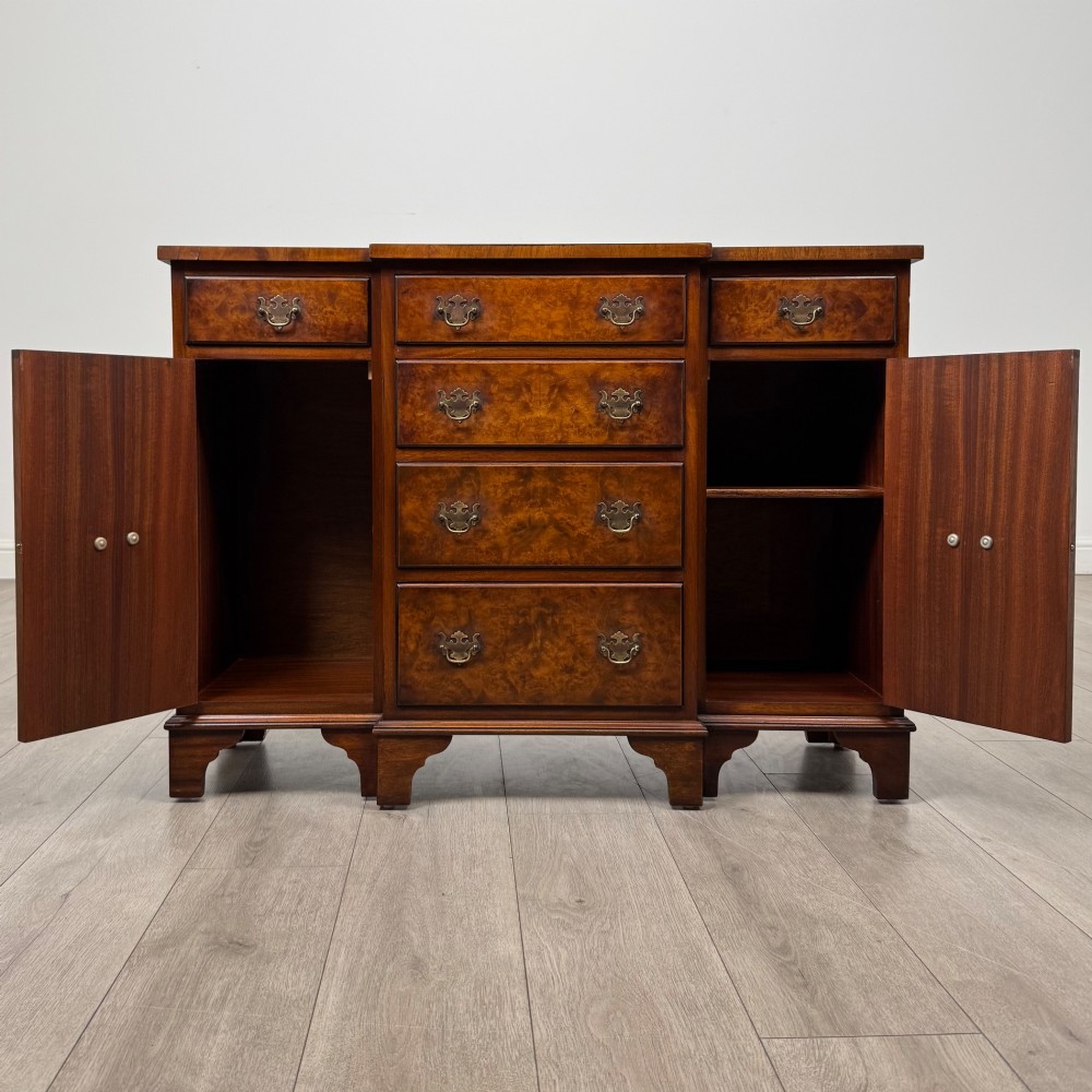An antique 20th-century small breakfront sideboard with figured burr walnut veneers, brass drop handles, four central drawers, and side cupboard doors. View II