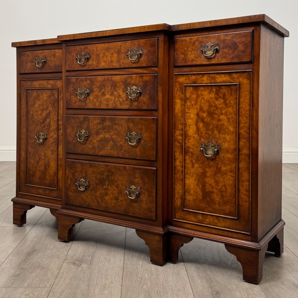 An antique 20th-century small breakfront sideboard with figured burr walnut veneers, brass drop handles, four central drawers, and side cupboard doors. View III