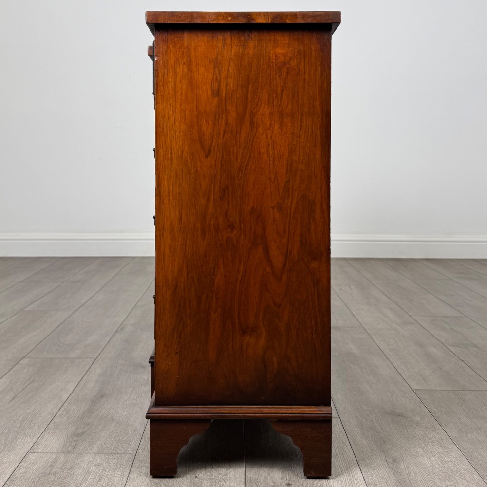 An antique 20th-century small breakfront sideboard with figured burr walnut veneers, brass drop handles, four central drawers, and side cupboard doors. View IV