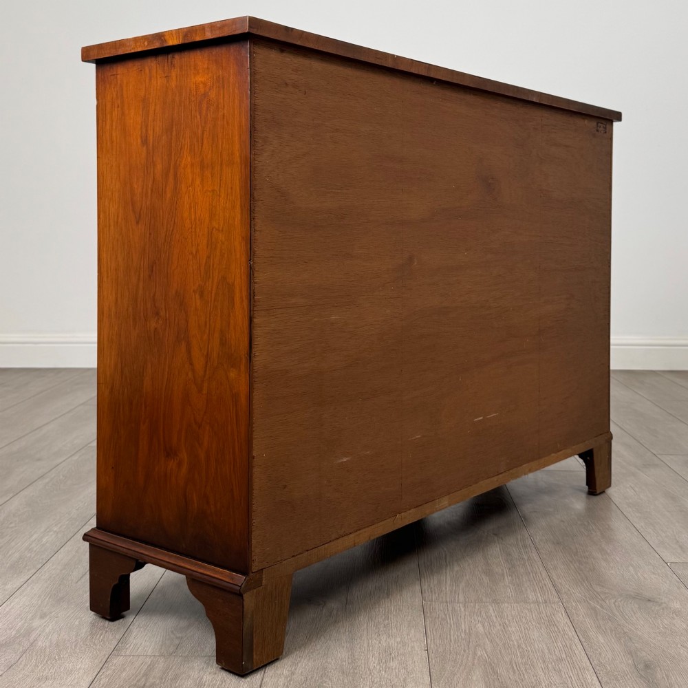 An antique 20th-century small breakfront sideboard with figured burr walnut veneers, brass drop handles, four central drawers, and side cupboard doors. View V