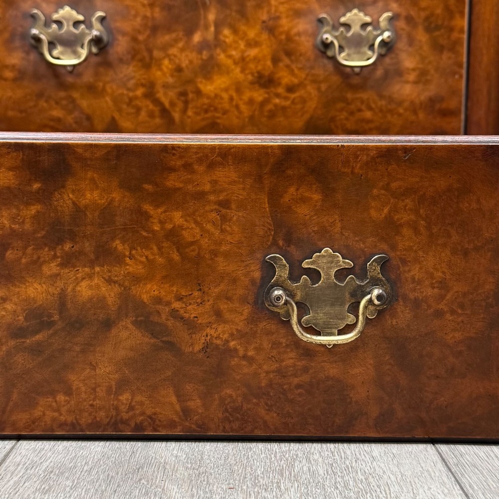 An antique 20th-century small breakfront sideboard with figured burr walnut veneers, brass drop handles, four central drawers, and side cupboard doors. View XII