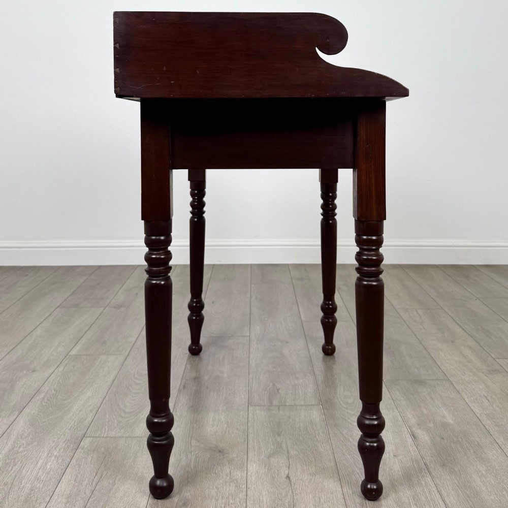 A 19th-century dark mahogany writing table featuring a raised gallery back upstand, two frieze drawers with turned handles, and four turned legs. View VII