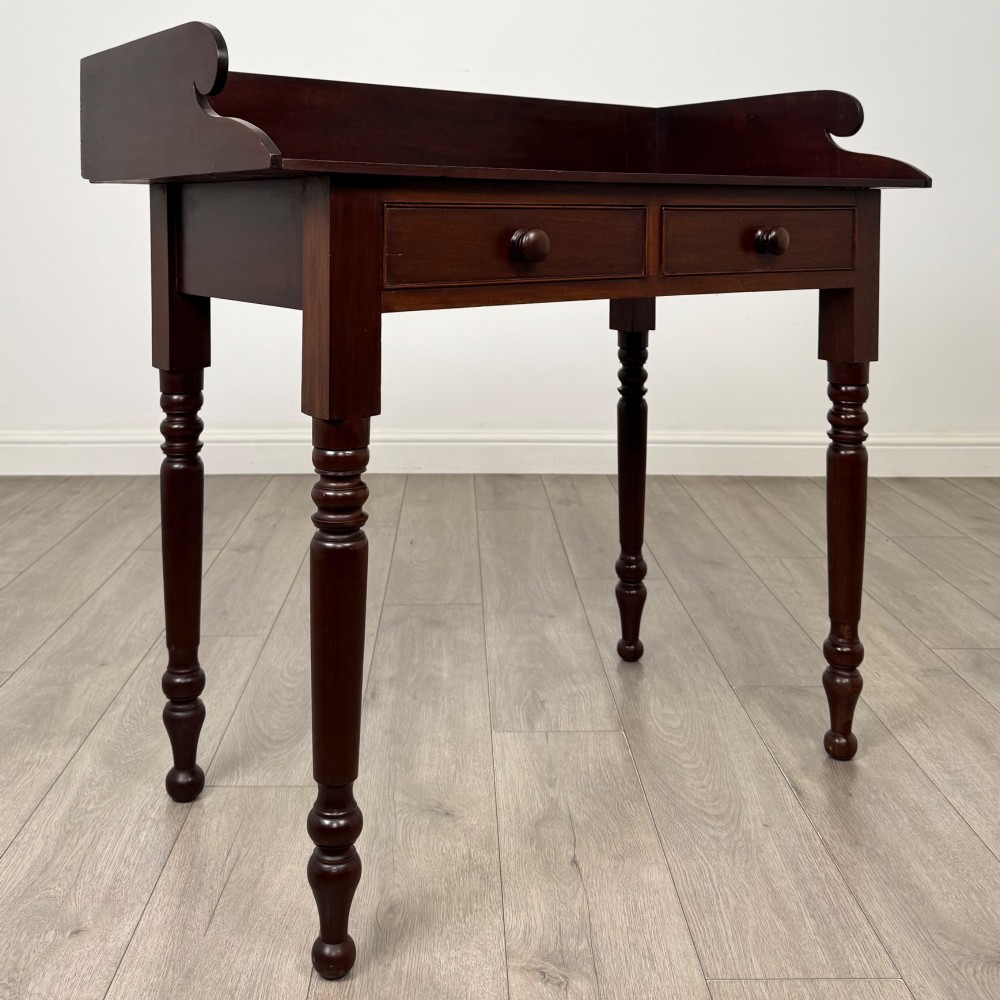 A 19th-century dark mahogany writing table featuring a raised gallery back upstand, two frieze drawers with turned handles, and four turned legs. View VIII
