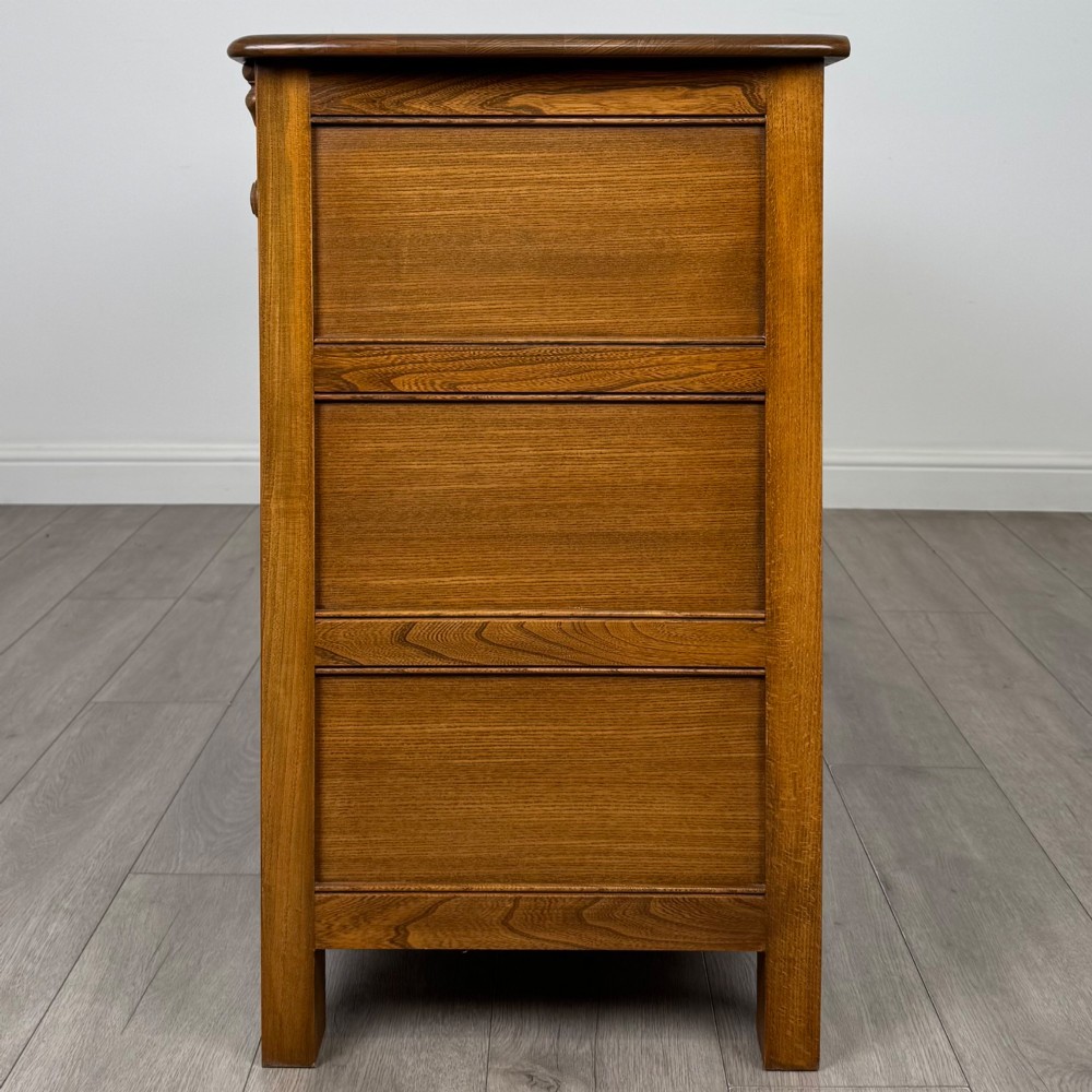 A warm brown solid oak sideboard with three drawers positioned above three fielded panel cupboard doors. View IV