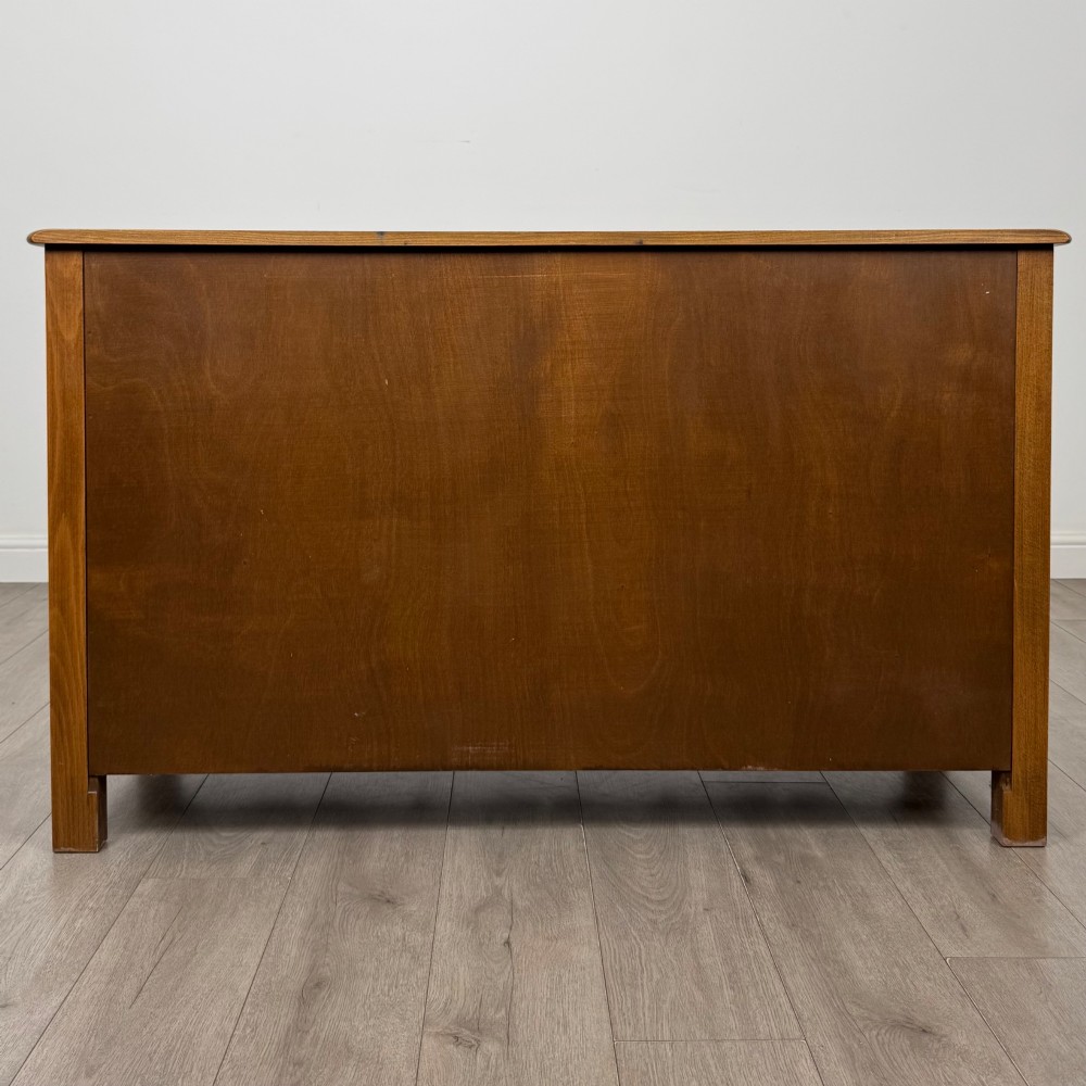 A warm brown solid oak sideboard with three drawers positioned above three fielded panel cupboard doors. View VI