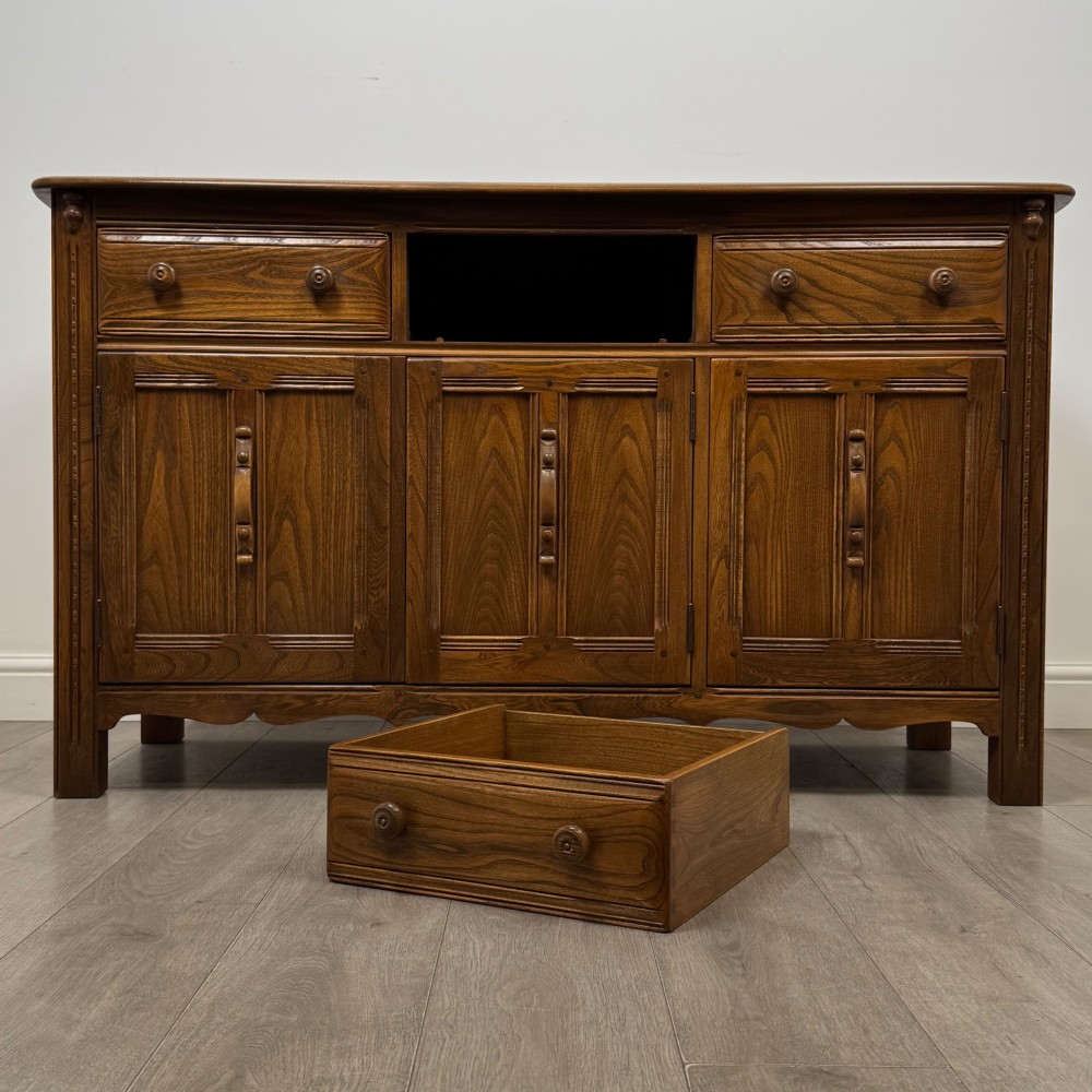 A warm brown solid oak sideboard with three drawers positioned above three fielded panel cupboard doors. View XI