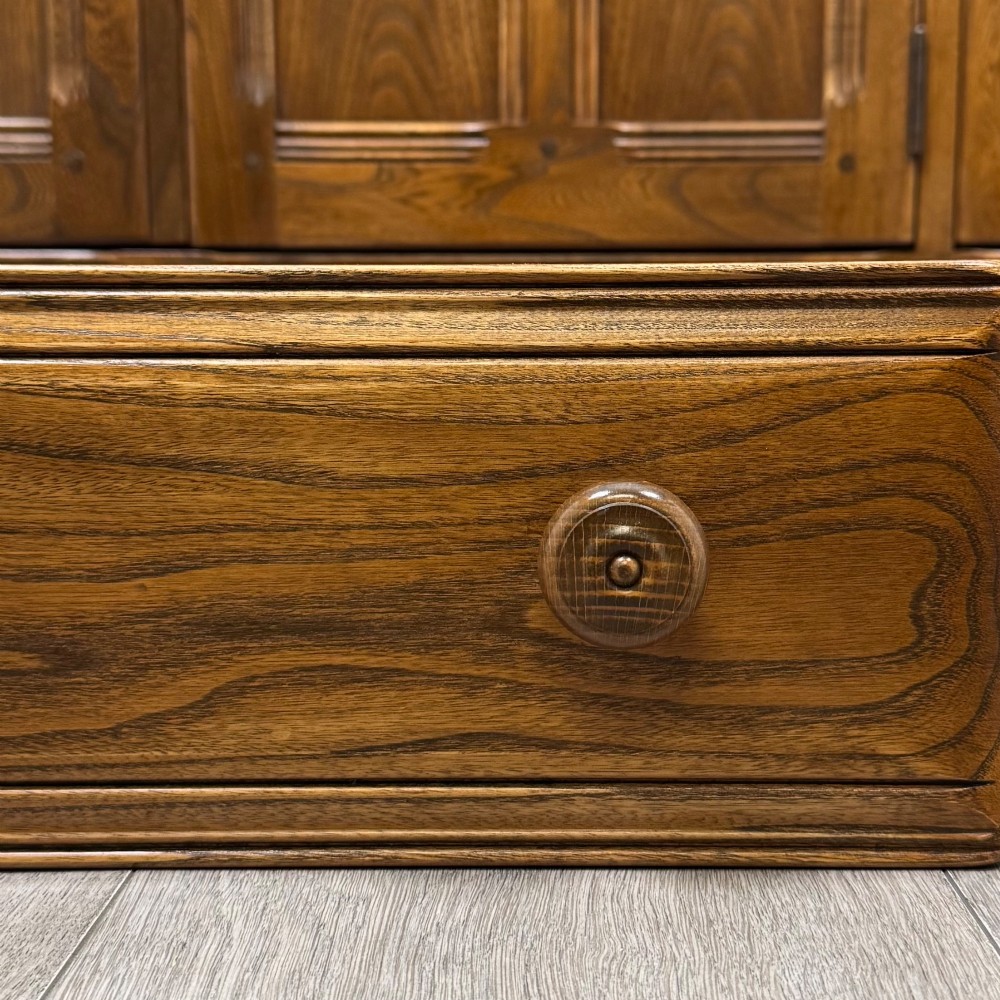 A warm brown solid oak sideboard with three drawers positioned above three fielded panel cupboard doors. View XII