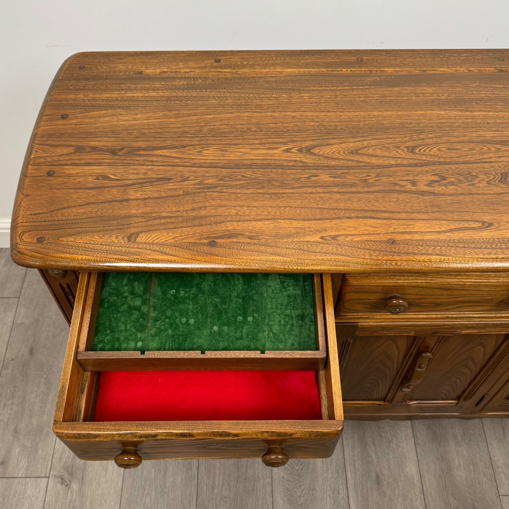 A warm brown solid oak sideboard with three drawers positioned above three fielded panel cupboard doors. View XIII