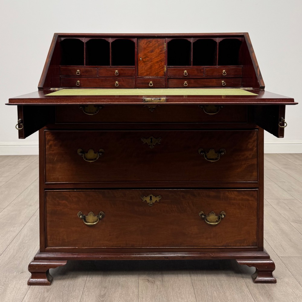 An 18th-century Georgian mahogany bureau featuring a sloped fall-front lid, brass batwing handles and escutcheons, three graduated drawers, and bracket feet. View II