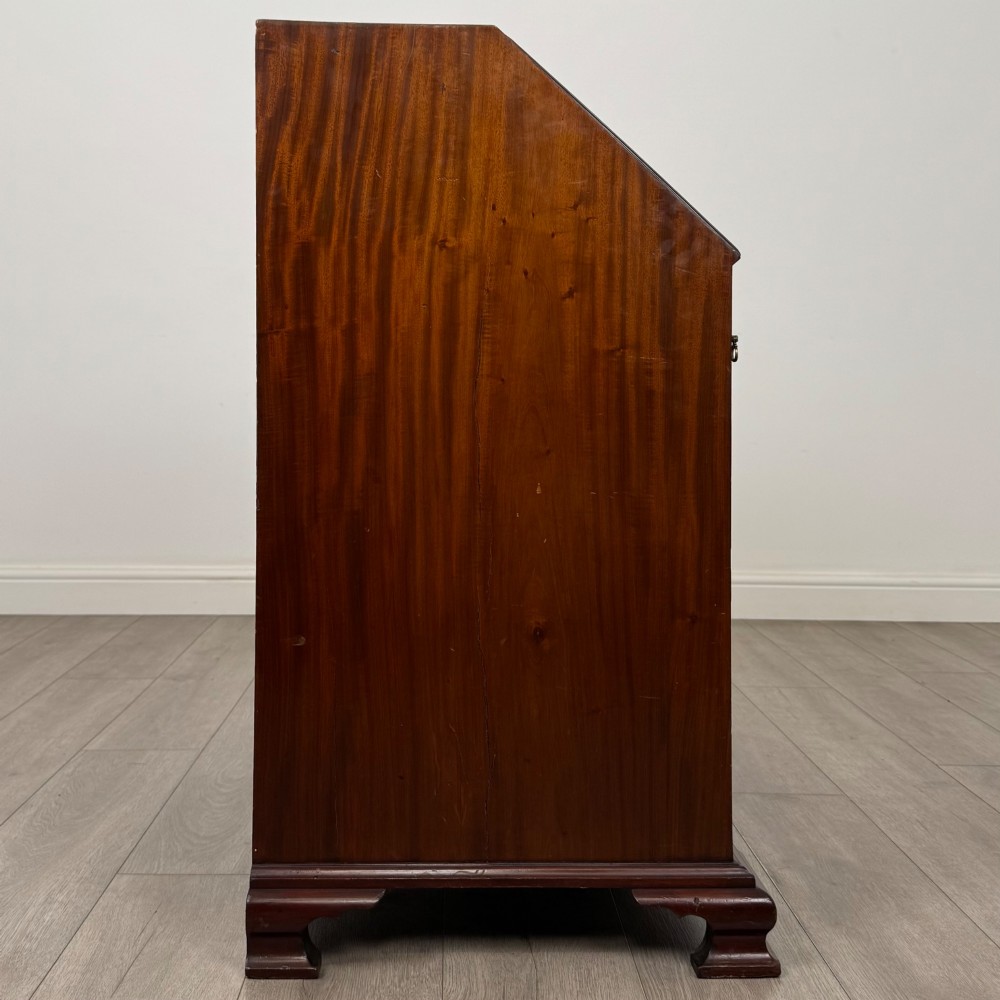 An 18th-century Georgian mahogany bureau featuring a sloped fall-front lid, brass batwing handles and escutcheons, three graduated drawers, and bracket feet. View VIII