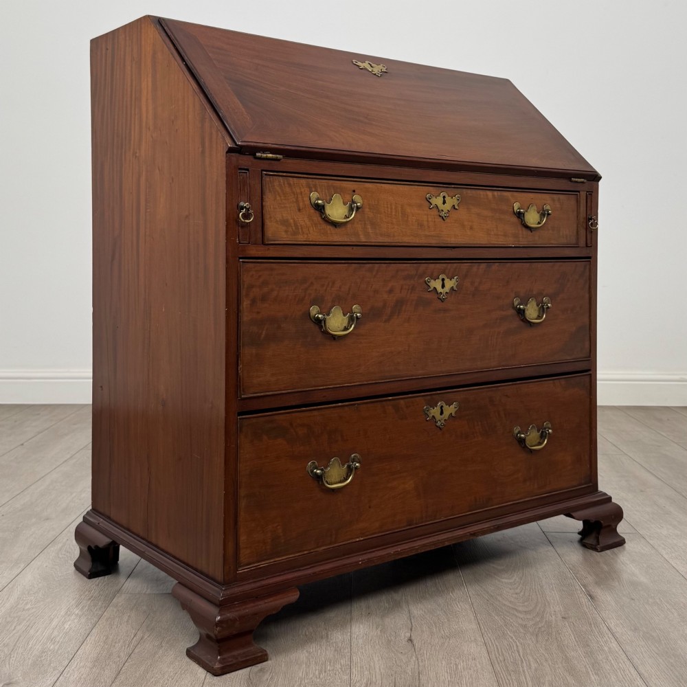 An 18th-century Georgian mahogany bureau featuring a sloped fall-front lid, brass batwing handles and escutcheons, three graduated drawers, and bracket feet. View IX