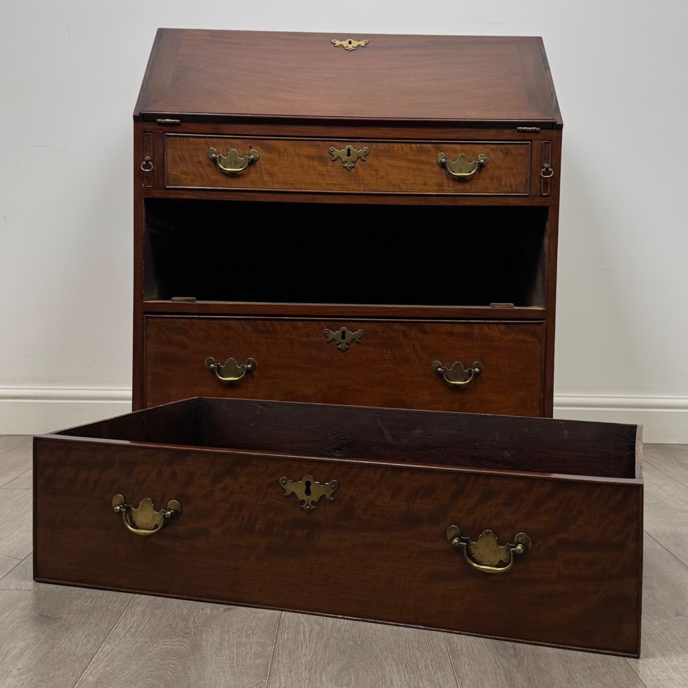 An 18th-century Georgian mahogany bureau featuring a sloped fall-front lid, brass batwing handles and escutcheons, three graduated drawers, and bracket feet. View XII