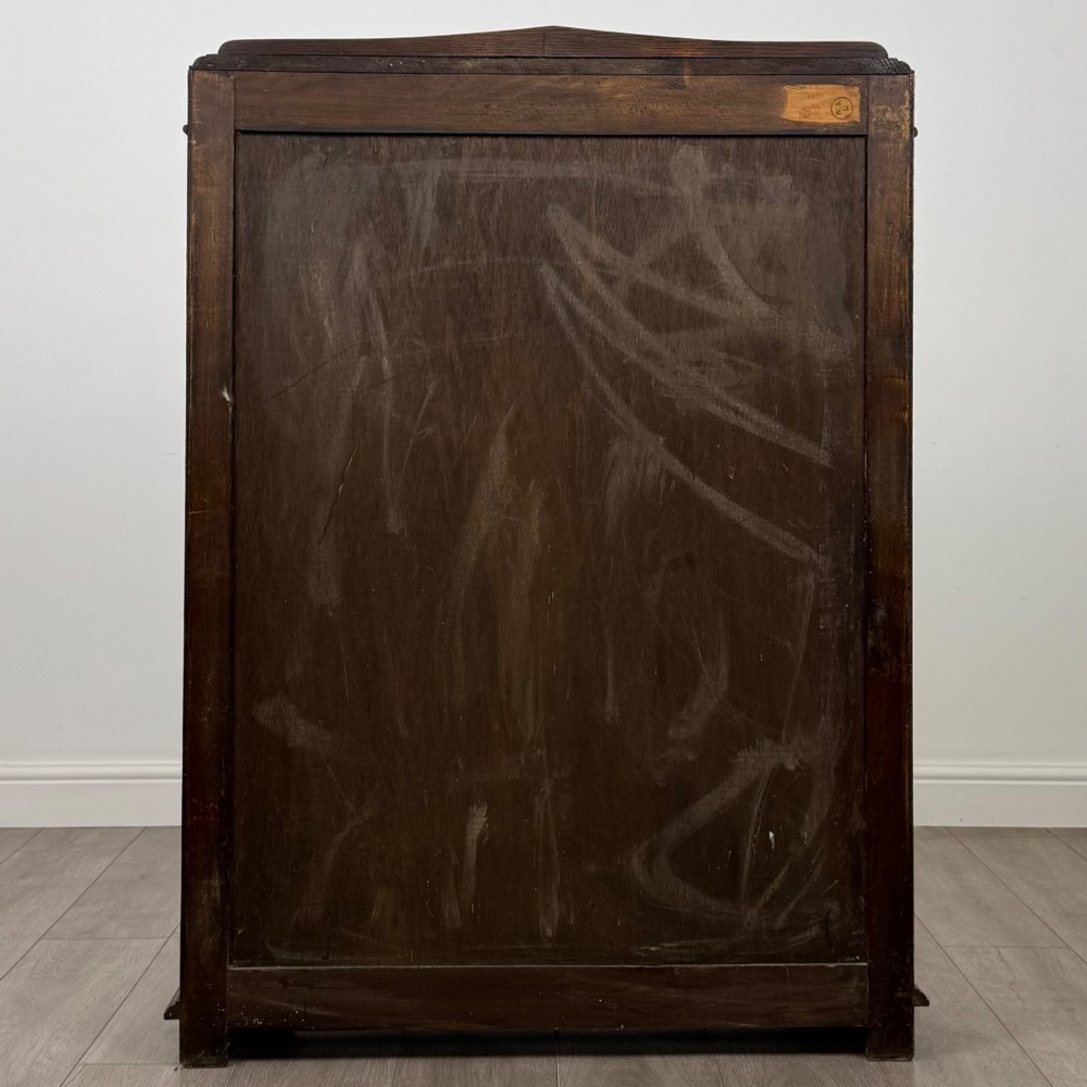 A twin-door dark oak display cabinet featuring leaded glass upper panels, carved decorative lower panels, and ornate metal hinges. View VI