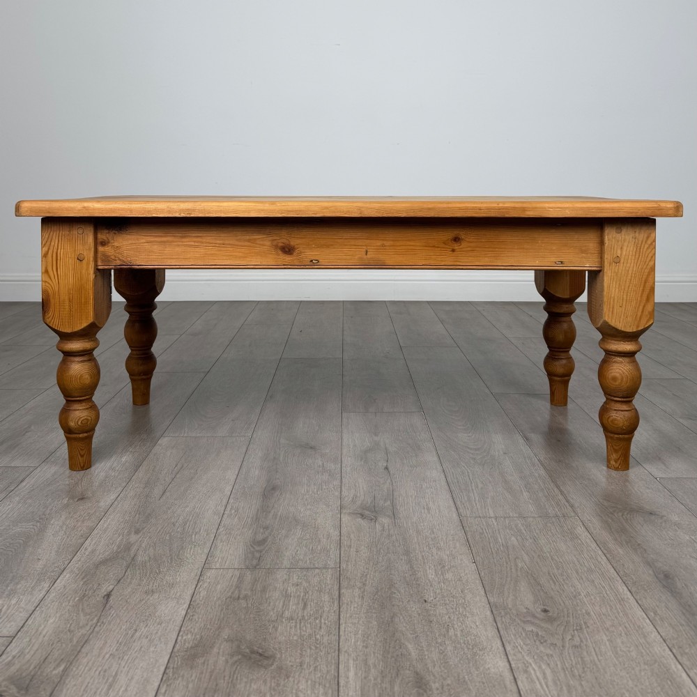 A low rectangular pine coffee table featuring turned baluster legs and visible wooden grain across its solid tabletop.