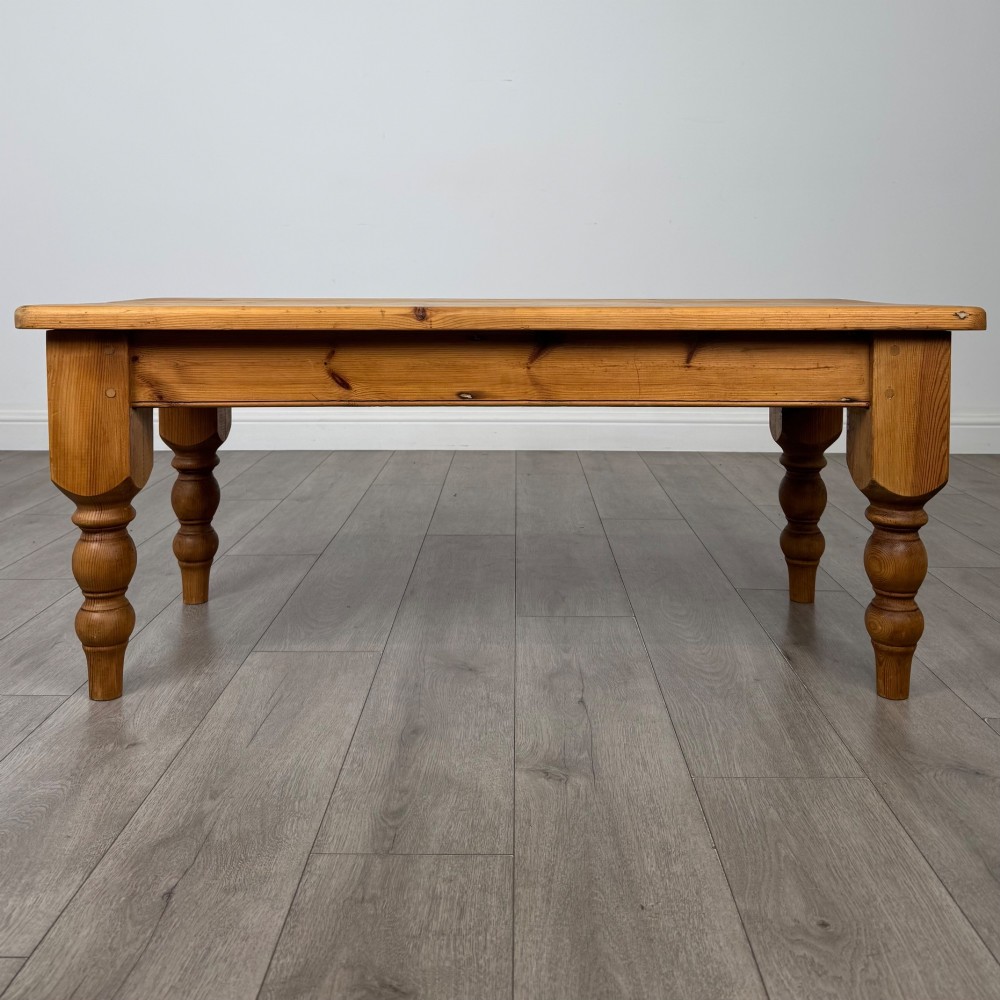 A low rectangular pine coffee table featuring turned baluster legs and visible wooden grain across its solid tabletop. View V