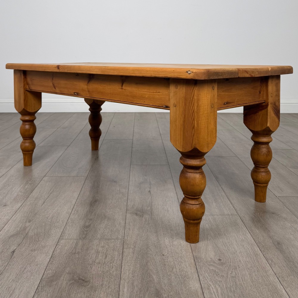 A low rectangular pine coffee table featuring turned baluster legs and visible wooden grain across its solid tabletop. View VI