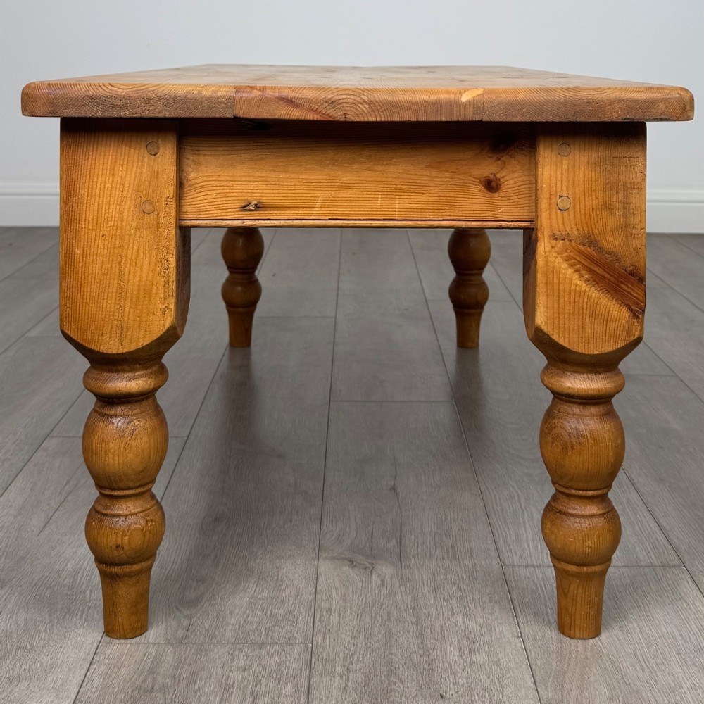 A low rectangular pine coffee table featuring turned baluster legs and visible wooden grain across its solid tabletop. View VII