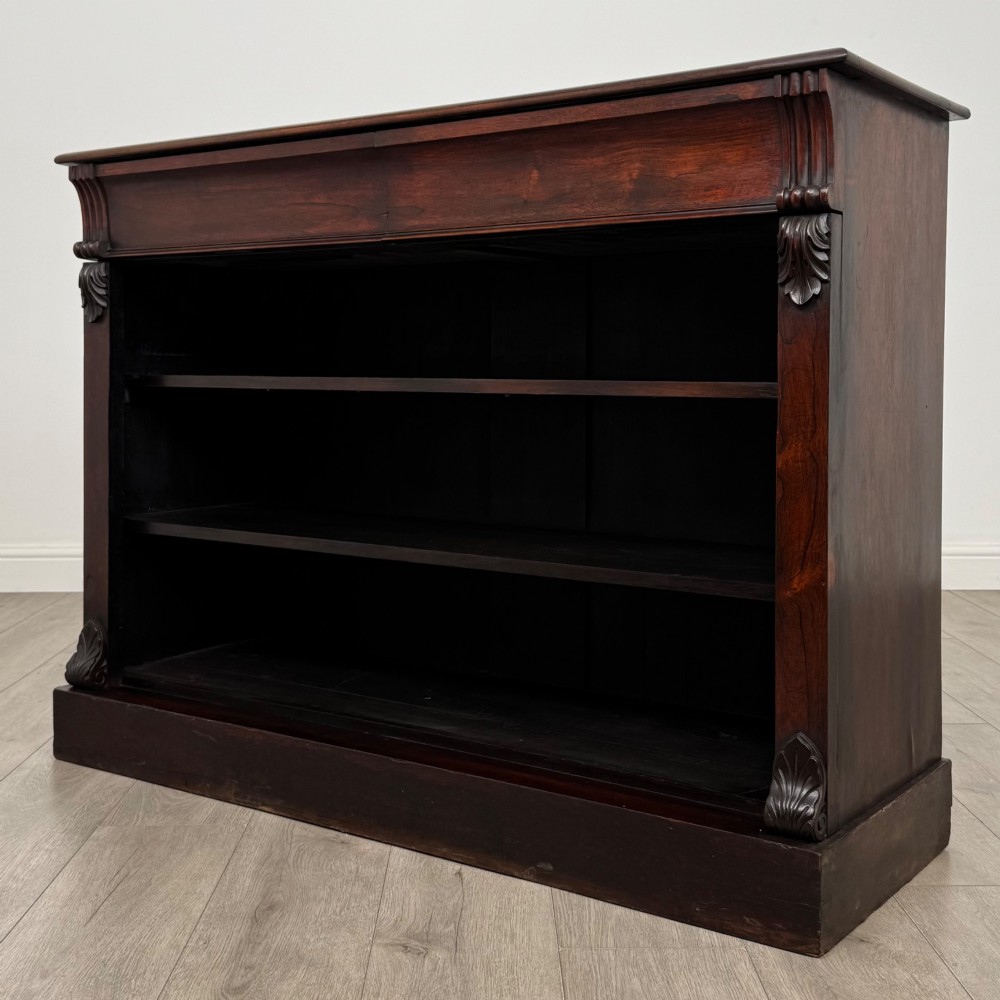 A low 19th-century Victorian rosewood open bookcase with two wide shelves, carved acanthus leaf capitals, and a solid plinth base. View II