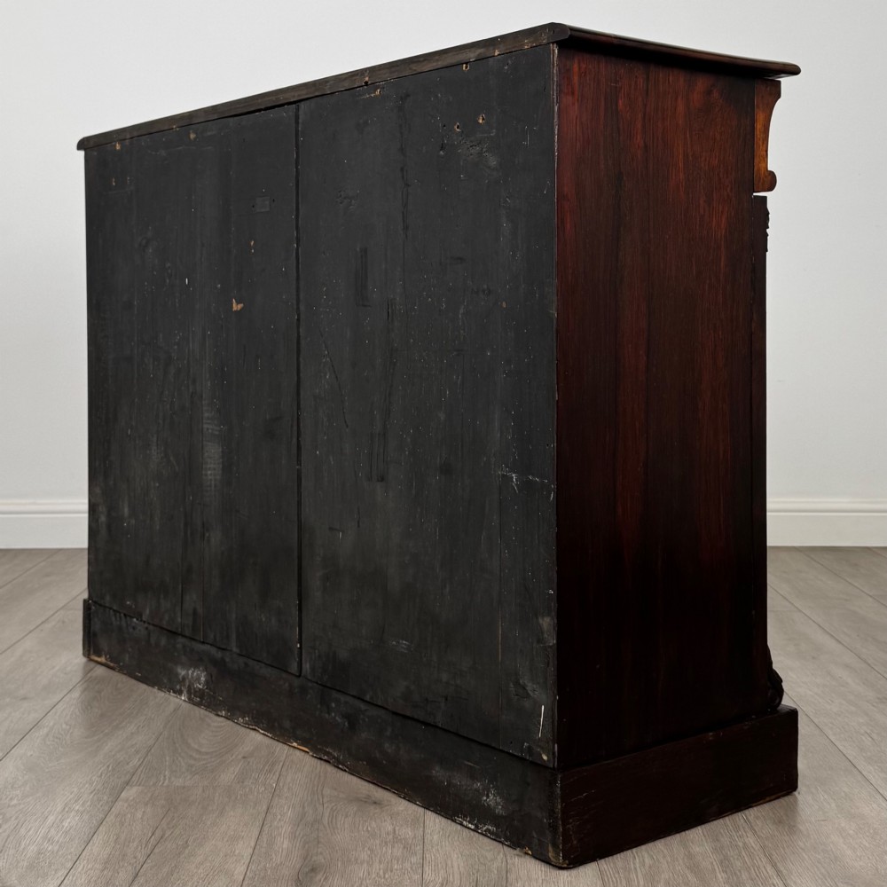 A low 19th-century Victorian rosewood open bookcase with two wide shelves, carved acanthus leaf capitals, and a solid plinth base. View VI