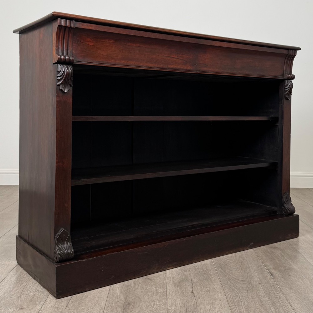 A low 19th-century Victorian rosewood open bookcase with two wide shelves, carved acanthus leaf capitals, and a solid plinth base. View VIII