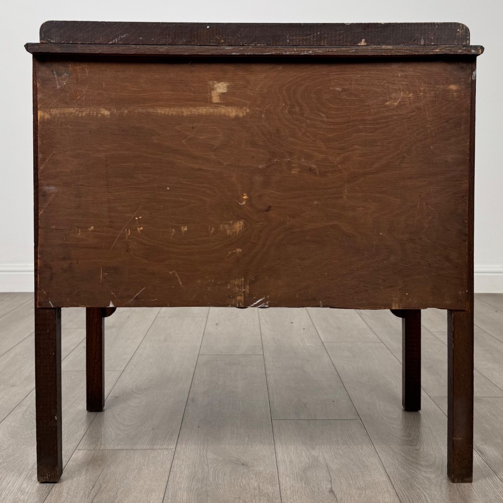 An antique golden oak chest of drawers featuring two wide drawers with stylised dark metal handles and a scalloped lower apron. View V