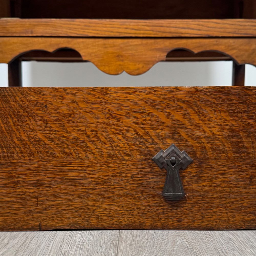An antique golden oak chest of drawers featuring two wide drawers with stylised dark metal handles and a scalloped lower apron. View XI
