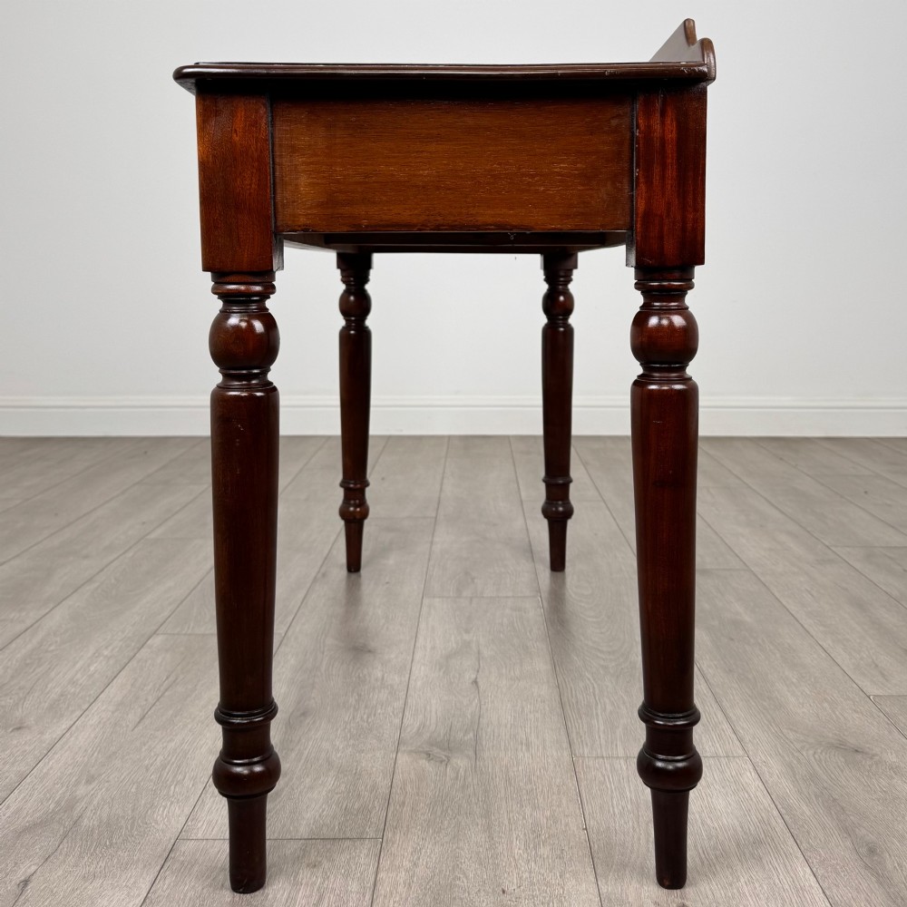 A Victorian mahogany writing table featuring two frieze drawers with brass ring handles and four turned legs. View III