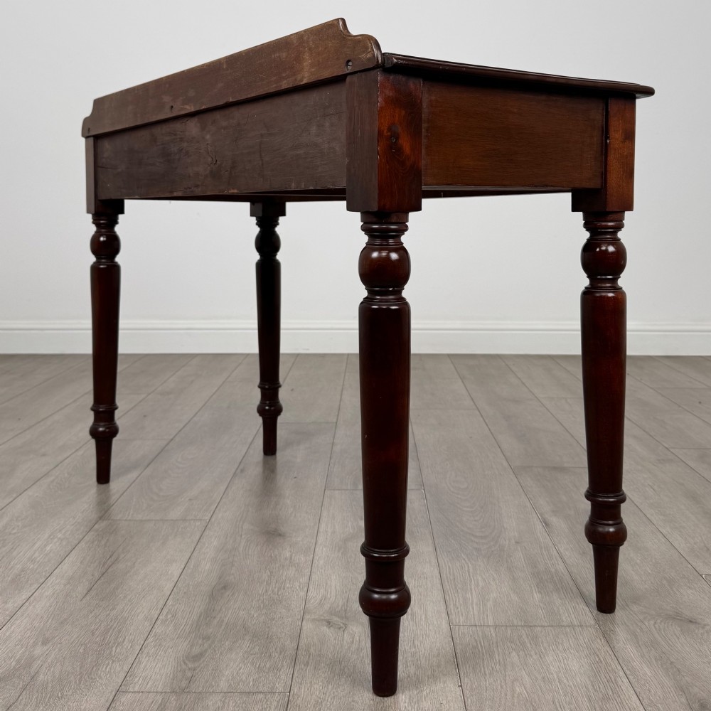 A Victorian mahogany writing table featuring two frieze drawers with brass ring handles and four turned legs. View VI