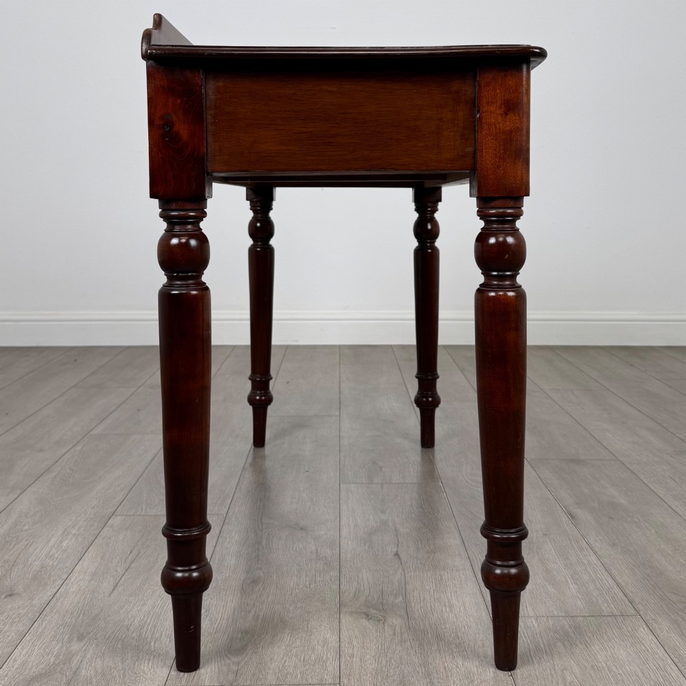 A Victorian mahogany writing table featuring two frieze drawers with brass ring handles and four turned legs. View VII