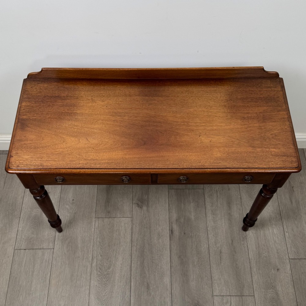 A Victorian mahogany writing table featuring two frieze drawers with brass ring handles and four turned legs. View IX