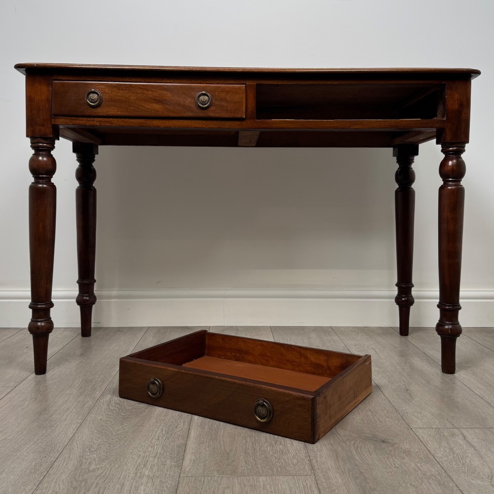 A Victorian mahogany writing table featuring two frieze drawers with brass ring handles and four turned legs. View X