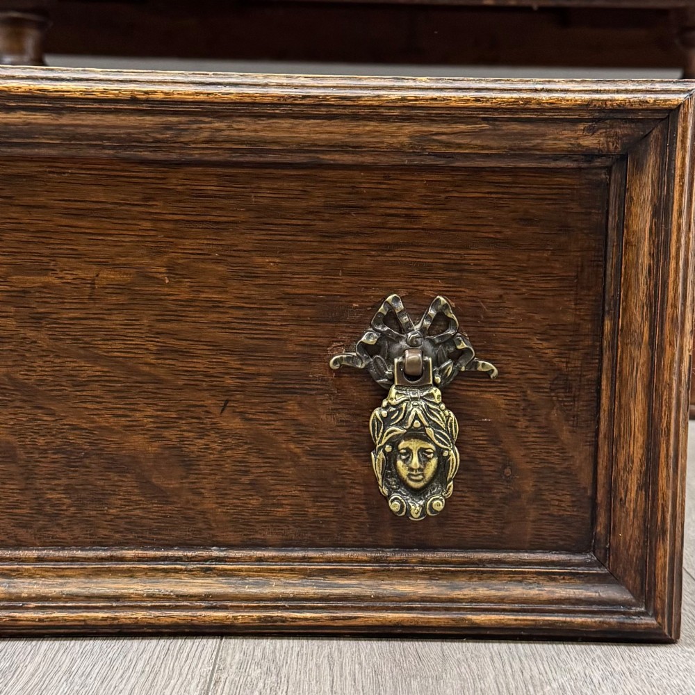 A dark carved oak sideboard featuring a raised gallery back, geometric octagonal panel doors, two central drawers with brass handles, and bulbous turned legs. View XII