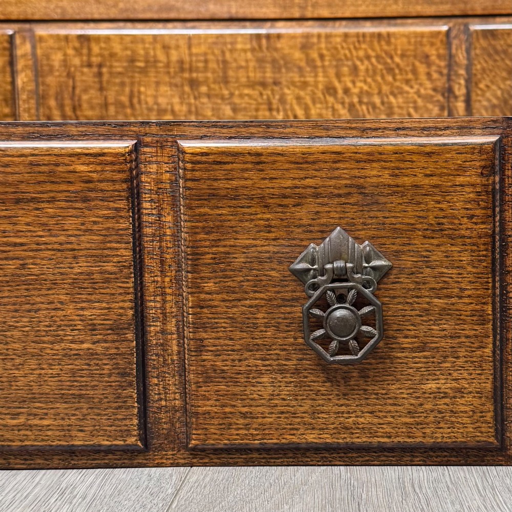 A twentieth-century dark oak chest of drawers featuring three drawers with geometric panel moulding, decorative drop handles, and shaped bracket feet. View XI