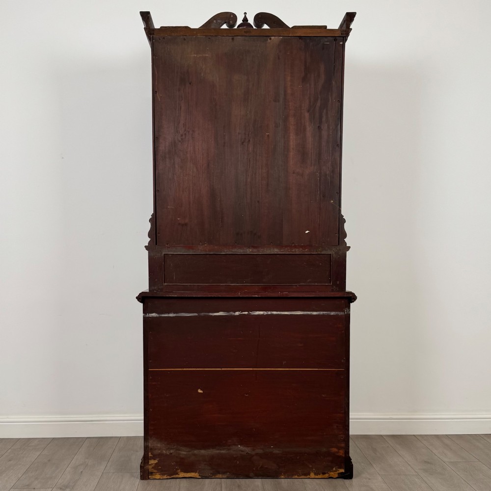A nineteenth-century dark mahogany glazed bookcase featuring a carved swan neck pediment, twin arched glass upper doors, and a lower two-door cabinet with carved panels. View VI