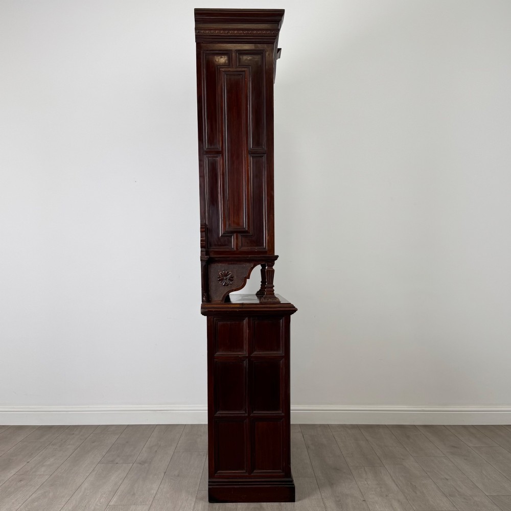 A nineteenth-century dark mahogany glazed bookcase featuring a carved swan neck pediment, twin arched glass upper doors, and a lower two-door cabinet with carved panels. View VIII